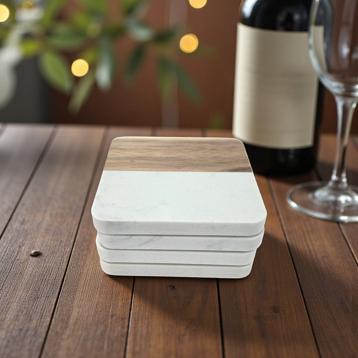 Stack of 4 square coasters with wood and faux marble on a table with wine bottle and glass in the background.