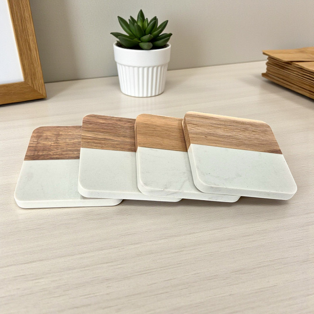 Set of 4 square wooden and white faux marble coasters on a light surface.