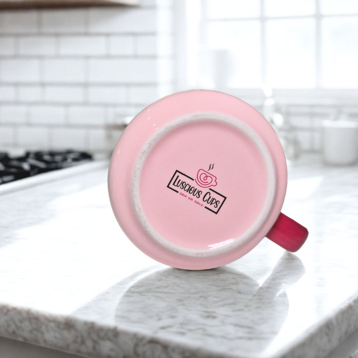 Pink mug with a visible brand logo of Luscious Cups on a kitchen counter