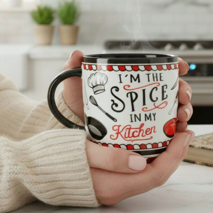 Person holding a mug with 'I'm the Spice in my Kitchen' text in a kitchen setting