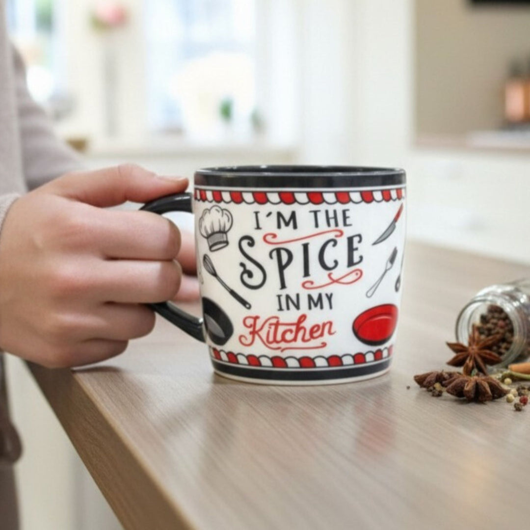 Person holding a mug with 'I'm the Spice in my Kitchen' text in a kitchen setting