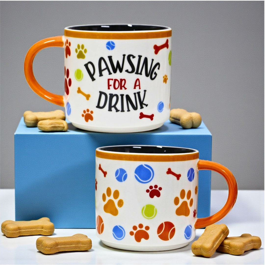 Back and front view of a ceramic mug with a wraparound dog themed design and text saying 'Pawsing for a Drink' 